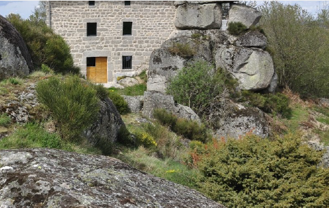 À Giberges : une bâtisse en pierre de taille adossée à d'énormes blocs de granite, entre genêts et genévriers.
